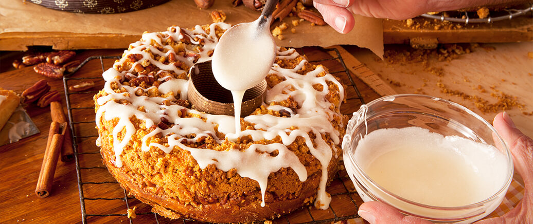 A coffee cake being covered in sweet icing