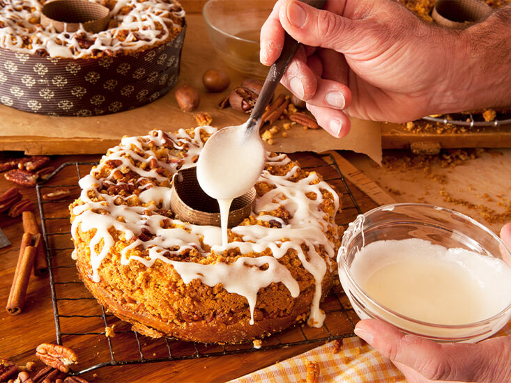 A coffee cake being covered in sweet icing