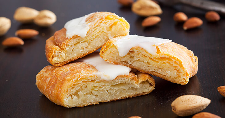 Slices of traditional Danish Almond Kringle, showcasing a flaky pastry filled with almond cream and topped with icing, embodying over 70 years of family tradition.