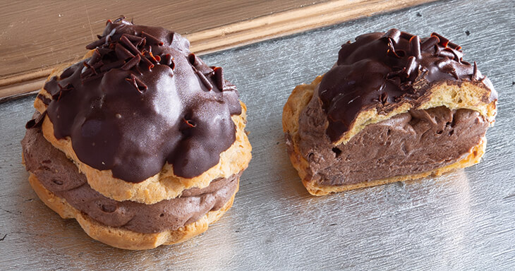 Our chocolate cream puffs are filled with decadent chocolate mousse and topped with fudge and dark chocolate curls.