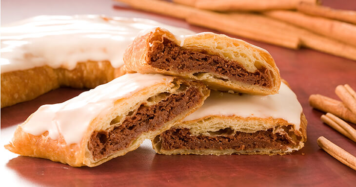 Slices of Cinnamon Roll Kringle featuring flaky pastry filled with buttery cinnamon and sugar, topped with sweet icing.