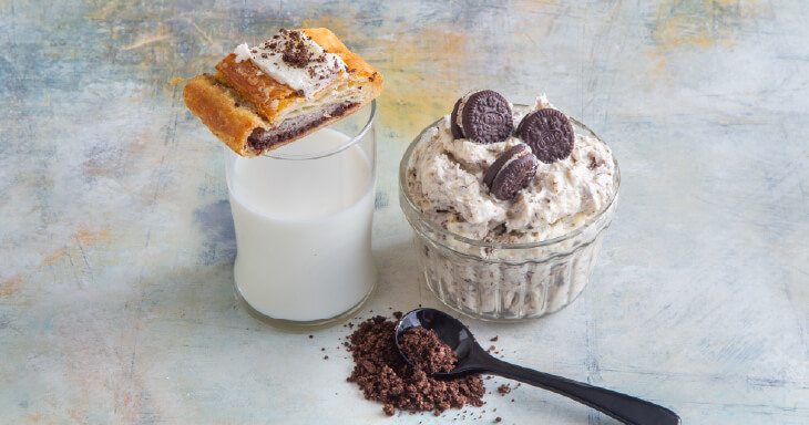 Cookies and Cream Kringle filling features a chocolate brownie base with rich vanilla filling and cookie pieces, topped with creamy vanilla bean icing and cookie crumbles.