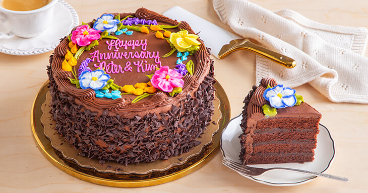 Anniversary cake with rich layers made from Dutch cocoa and buttermilk, filled with dark chocolate silk and topped with creamy chocolate buttercream, adorned with chocolate curls and a personalized message.