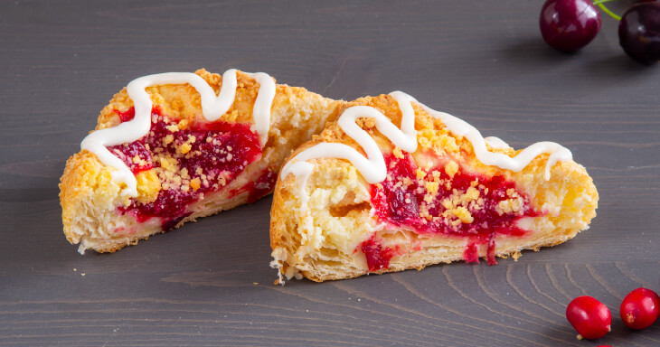 A Danish pastry featuring flaky layers of smooth cheesecake, topped with homemade cherry and cranberry compote. Perfect for dessert lovers!