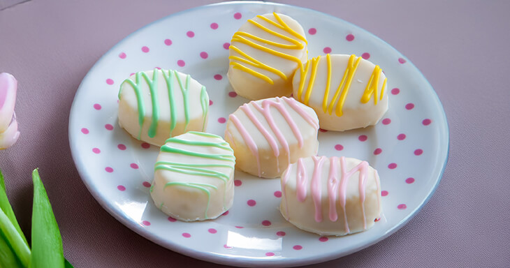 Hand-dipped Easter egg petit fours, charming white cake bites beautifully decorated to complete your Easter celebration.