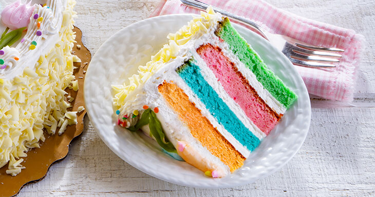 Celebrate Easter with a vibrant layer cake in orange, blue, pink, and green. Frosted with buttercream and decorated for a cheerful Easter vibe!