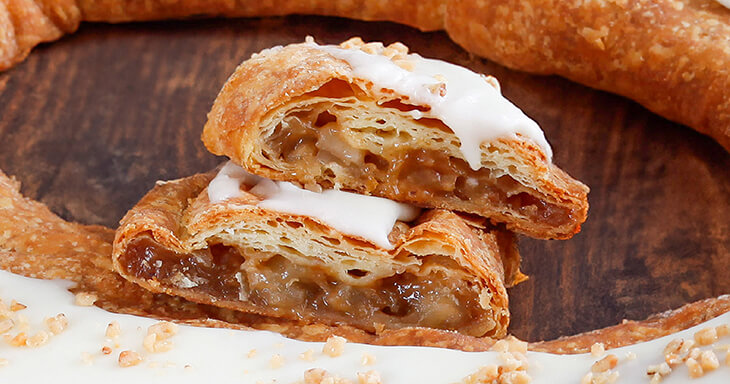 Close-up of Harvest Kringle featuring crisp apples sprinkled with cinnamon and toffee bits, topped with creamy icing