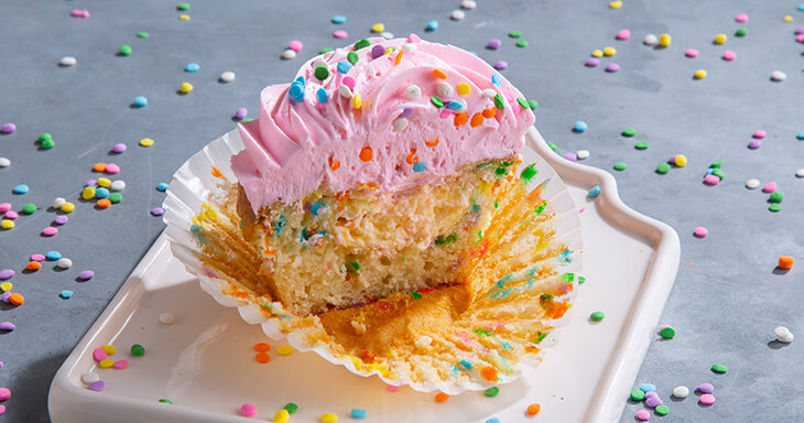 An extra-large birthday cupcake featuring colorful buttercream frosting and candy pieces, ideal for festive parties and celebrations.