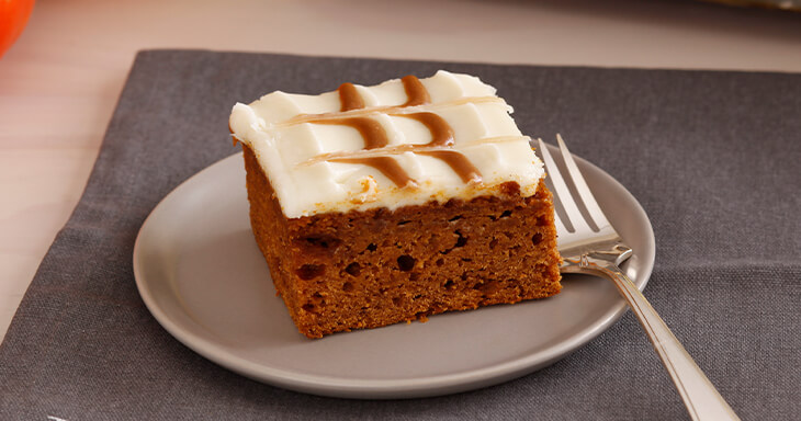 Delicious pumpkin brownies topped with cream cheese frosting and a drizzle of caramel, showcasing the essence of autumn in a decadent dessert.