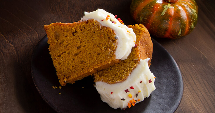 A delicious pumpkin bundt cake with cream cheese frosting, adorned with fall sprinkles.